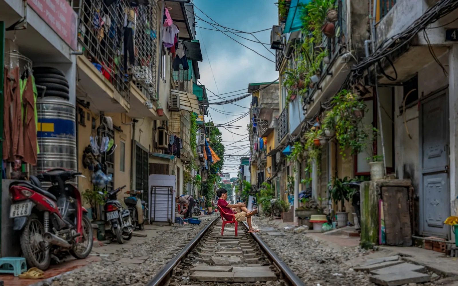 Nhà ga đường sắt sơn vàng nhạt nhìn từ phía phố, người đi bộ trên vỉa hè