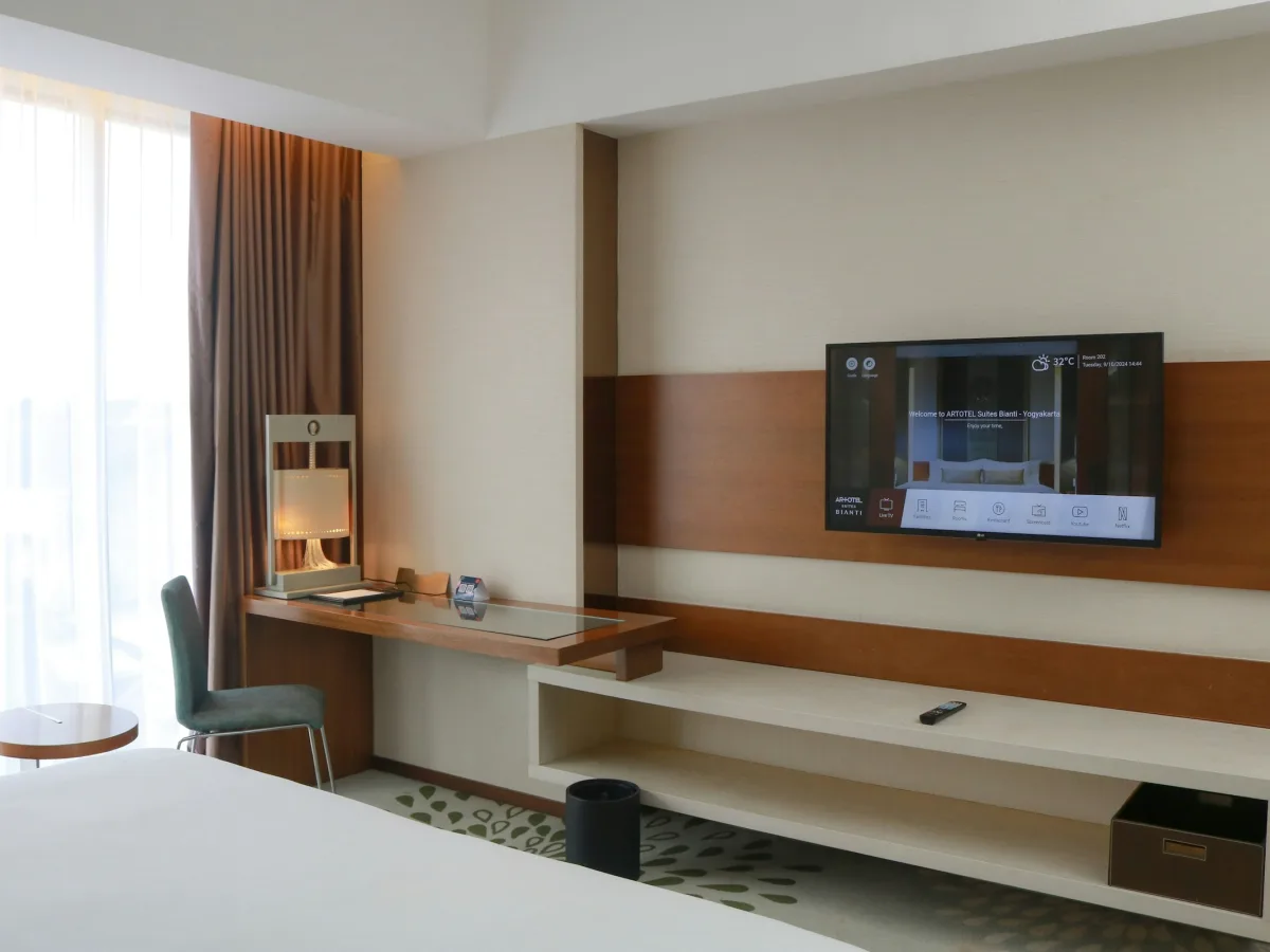 Góc phòng có kệ TV treo tường, điều hòa và móc treo đồ cạnh cửa